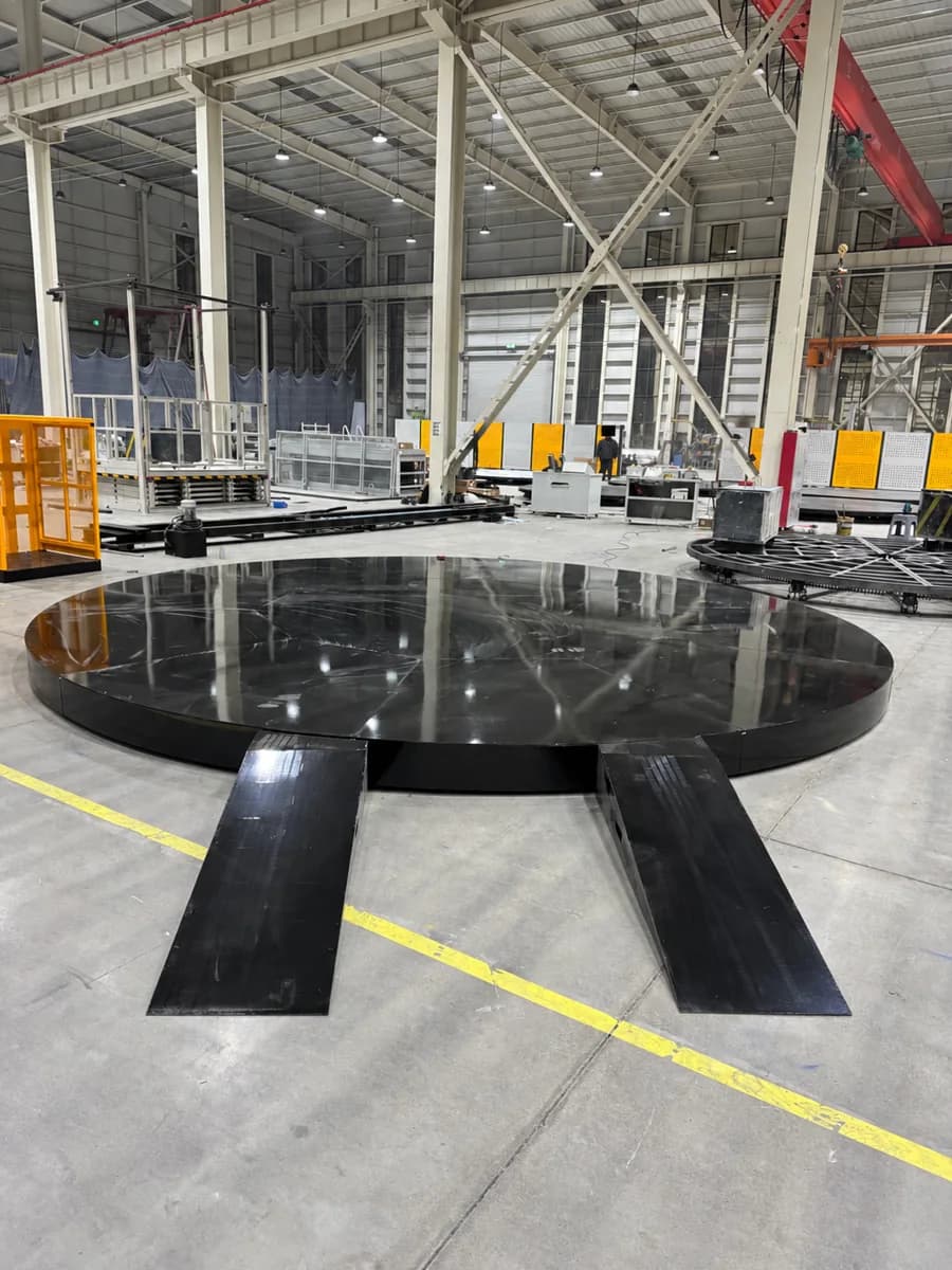 Black circular platform with two approach ramps in a workshop